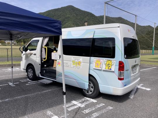 広い駐車場に設置された青いテントの横に停車しているマルチタスク車両の写