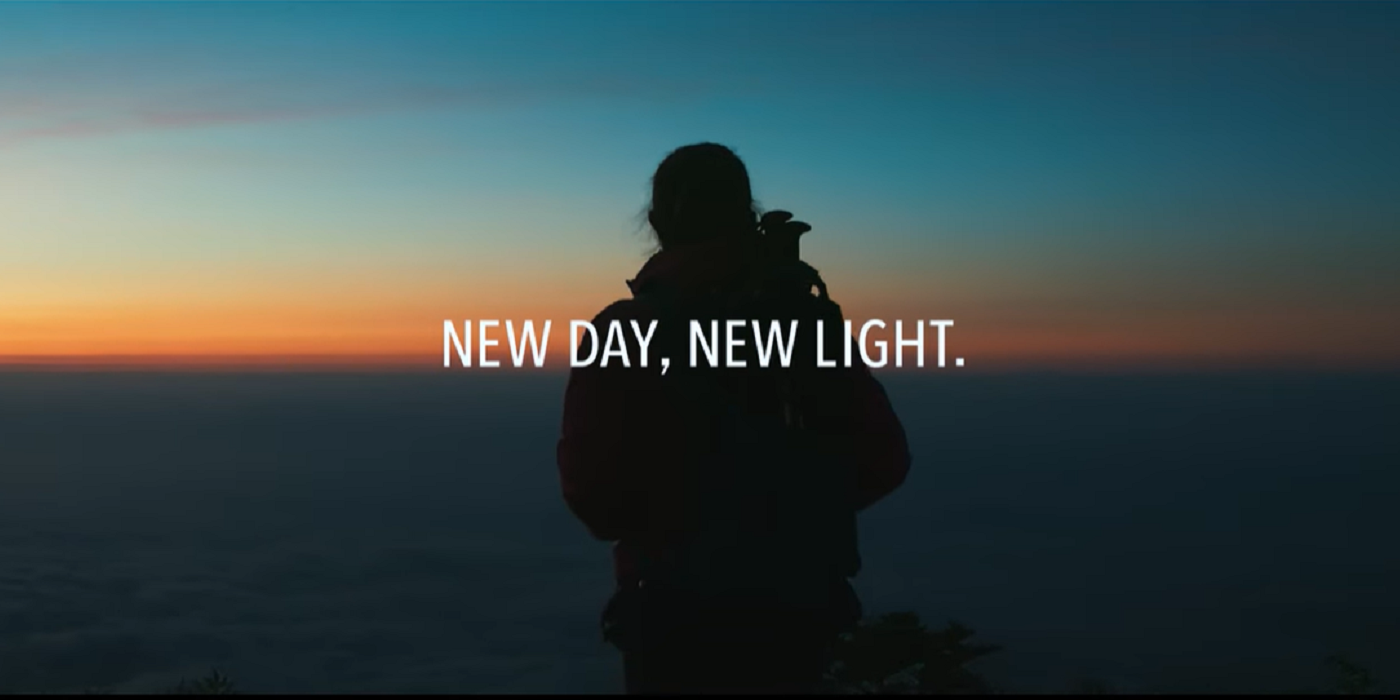 NEW DAY,NEW LIGHT.山頂から朝焼けの空を望む男性の後ろ姿