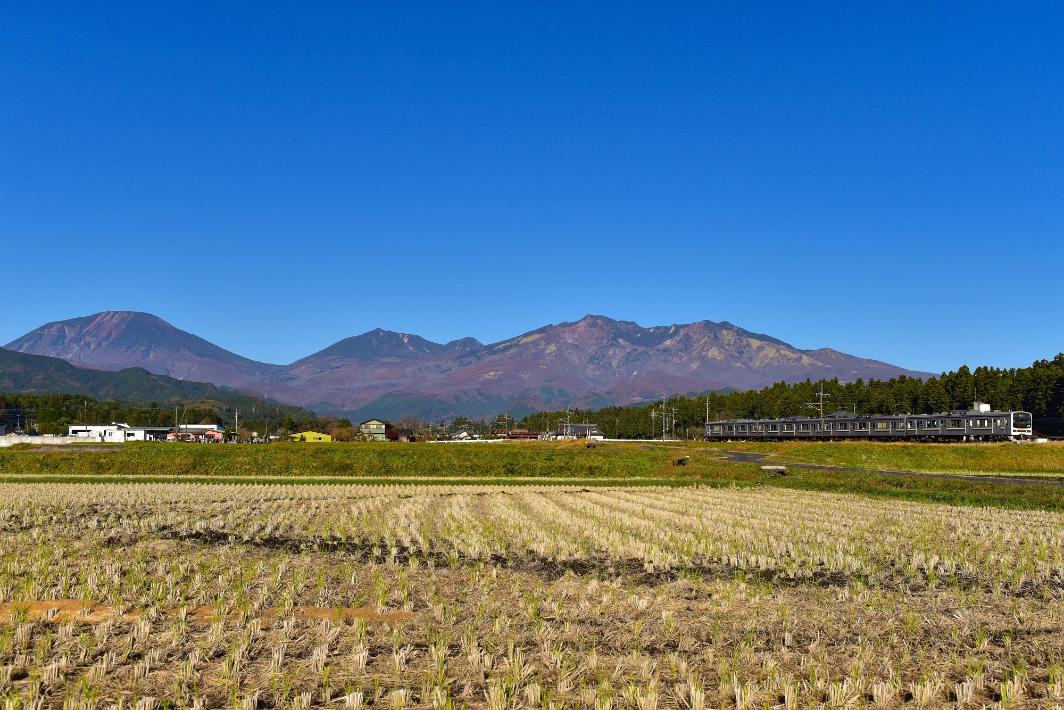 秋晴れの下の日光連山と電車