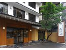 門の近くに木があり、趣のある和風の石畳の玄関を斜め前から写した写真