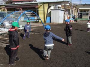 青と緑の帽子を被った子ども達がうんていの周りで遊んでいる写真