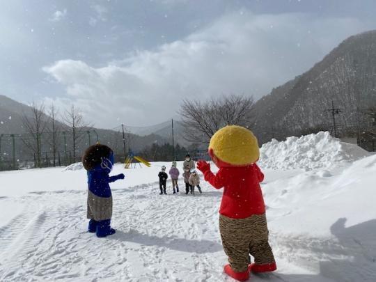 雪が積もった園庭で、子ども達がきぬちゃん・かわちゃんに豆をまいている写真