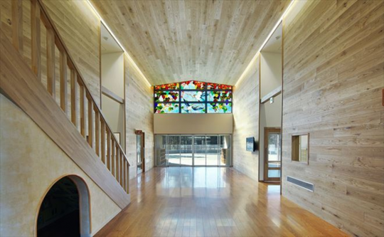床、壁、天井などに木材が使用され、入口付近にはステンドガラスの窓がある園内エントランスの写真