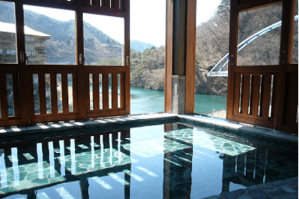 宿泊施設にある大きなお風呂と、窓から見える風景が写し出された鬼怒川・川治の写真