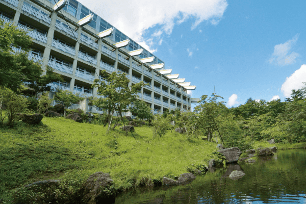 青空の下、緑の芝の奥に建っている大江戸温泉物語 日光霧降の外観写真