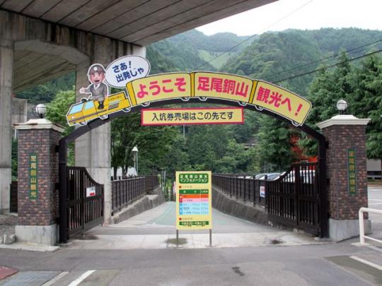 「ようこそ 足尾銅山観光へ！」と書かれた看板がある、券売場へ続く入り口の門の写真