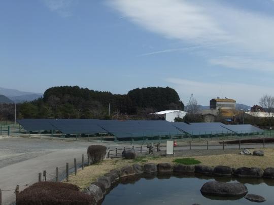 青空の下ソーラーパネルと周囲に大きな石が敷き詰めてある水域の写真