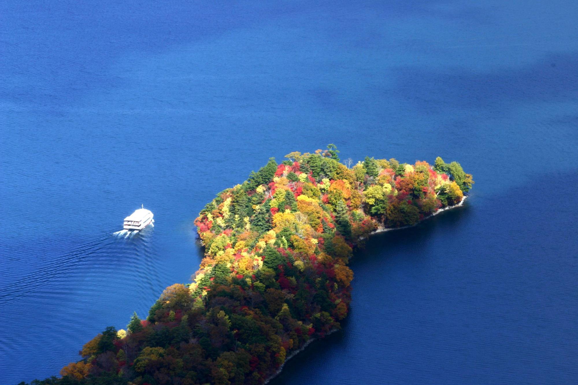 真っ青な海に浮かぶ紅葉で彩られた八丁出島を上空から写した写真