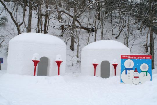 雪が積もった林の前に二つの鎌倉がある写真