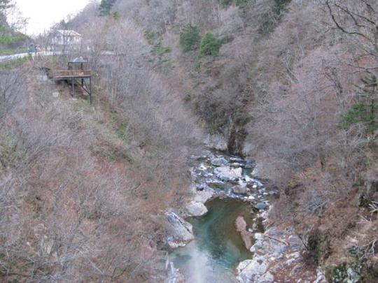 谷の間の間欠泉と展望台を橋の上から写した写真