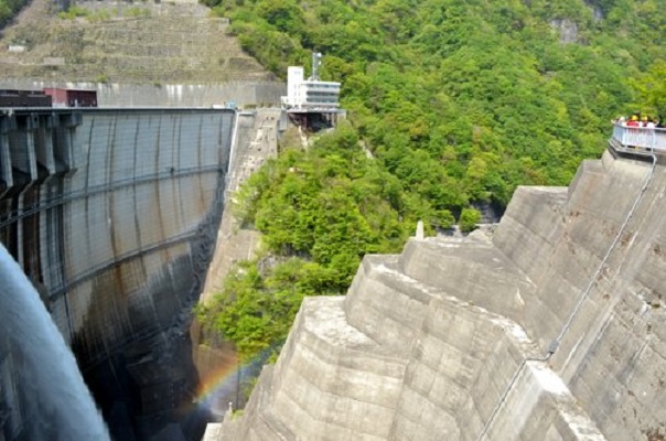 右側に高さのあるコンクリートの壁、左側の壁からは水が勢いよく放水している川治ダムの写真