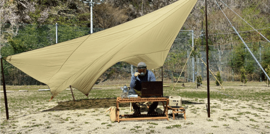 テントを張り川治温泉薬師の湯キャンプ場でくつろいでいる男性を写した写真