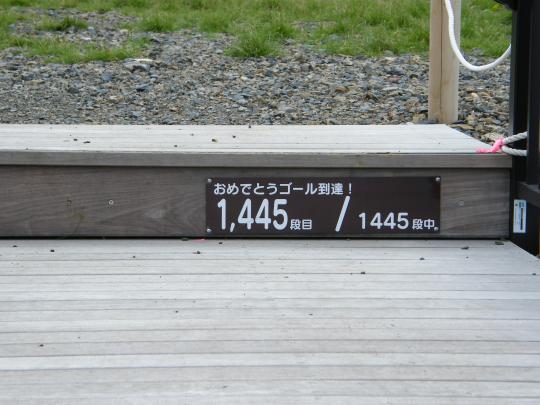 木の階段に「おめでとうゴール到達！1445段中1445段目」と案内版が取り付けられている写真