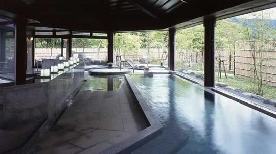 L字型のお風呂が浴場一面に設置されており、目隠し用の竹の柵がされた庭も見渡せるようになっている大浴場の写真