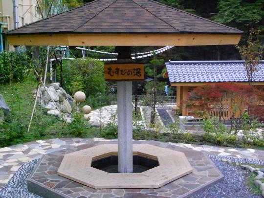 屋根の柱に「むすびの湯」と書かれた木製の小さな看板が設置してある足湯の写真