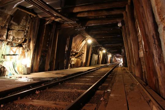 地下のトンネルに線路が敷いてあり、電気が点灯している写真