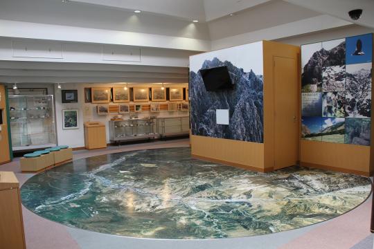 衛星写真の地図が転写された円卓のような展示物や、風景写真が展示された館内の写真