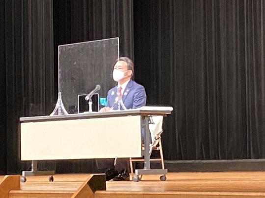 パーテンションが設置されたテーブルの席に市長が座り講話をしている日光市自治会長研修会の様子の写真
