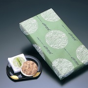 お皿に盛られたクッキー、淡い緑色の包装紙で包装された箱入りの虎彦製菓のきぬの清流の写真