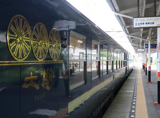 駅のホーム側から撮影した黒い車体に金色で車輪の模様が施されたSLの写真