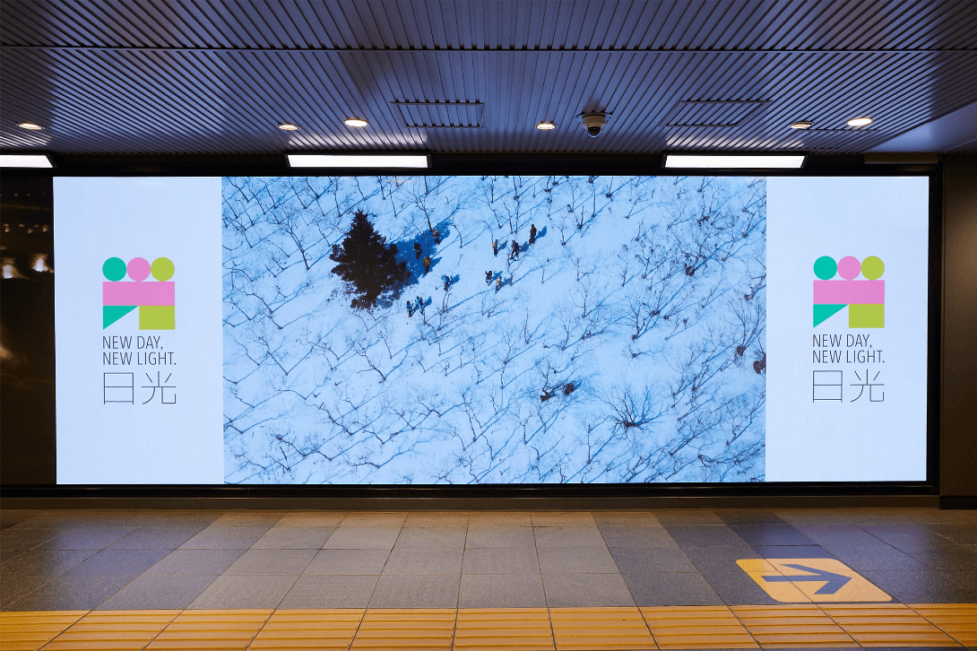 駅構内に、葉が落ちた木々と積もった雪がデジタルサイネージに映し出された「NEW DAY, NEW LIGHT. 日光」プロジェクトの写真
