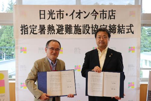 締結書をもつ粉川市長とイオン今市店のかた