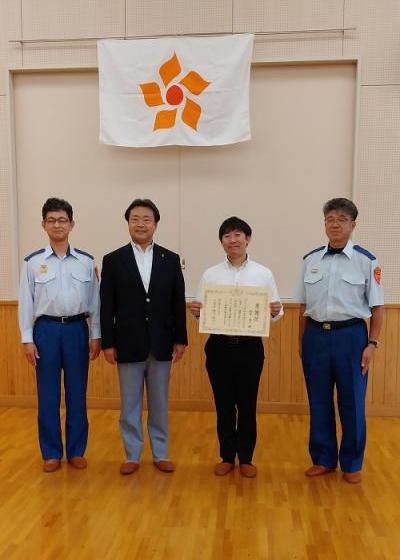 消防士の方が2名、真ん中に市長と賞状を持った原子泰一さんが並んで記念撮影をしている写真