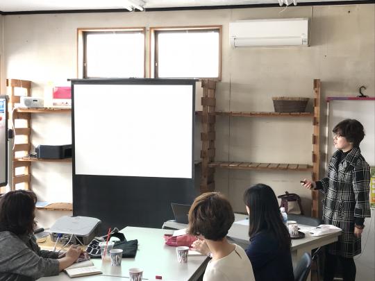 講演者がプロジェクタを使って参加者に話をしている写真