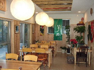 4人掛けのテーブルが3卓並び、天井から丸い和紙で作った和風の照明が吊るされた、こもれ日の里ことじの店内写真