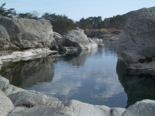 巨大な岩の間に川が流れている「籠岩」の写真