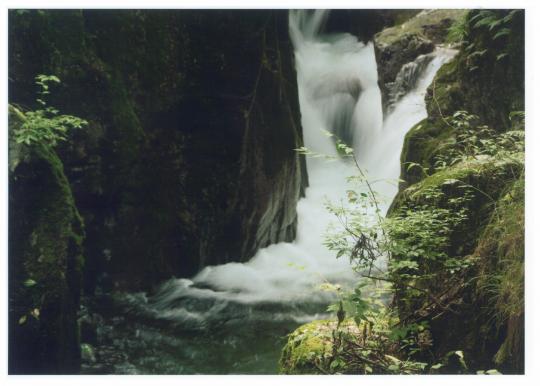 岩と岩の間を流れ落ちる鶏鳴山の滝の写真