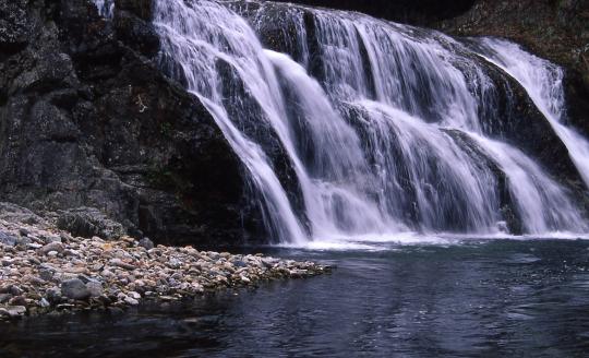 段になった岩肌を幅広く流れ落ちる不動滝の写真