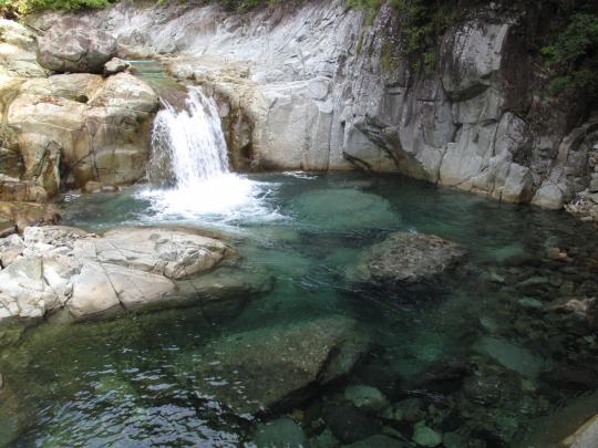 透明度のある滝つぼに流れ落ちる小滝の小滝の写真