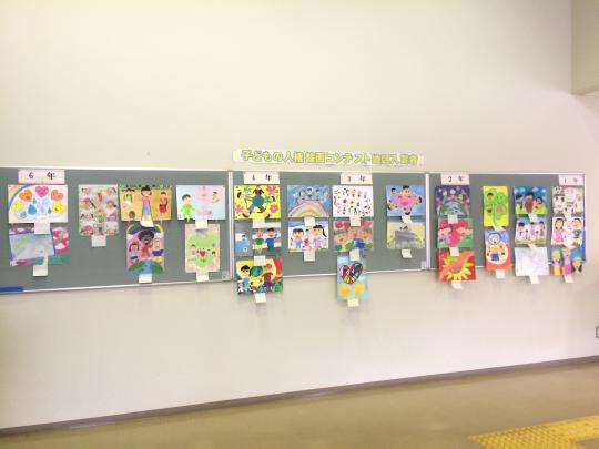 「子どもの人権絵画コンテスト地区入賞者」と書かれた紙が壁に貼られており、1年生から6年生の入賞者の作品が掲示板に展示されている写真