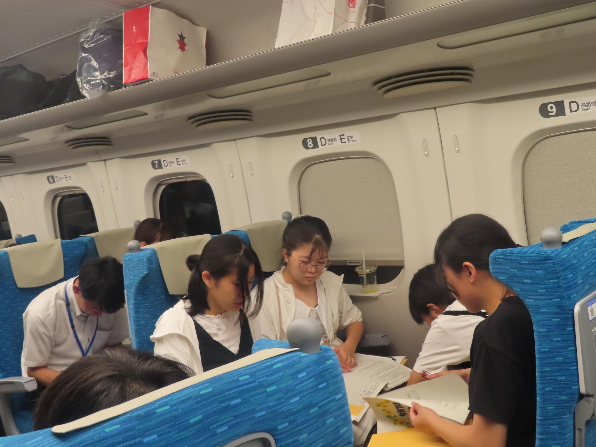 帰りの新幹線で発表に向けてグループ活動をする様子