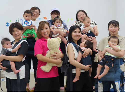 大勢の母親が乳幼児を抱きかかえて記念撮影している写真