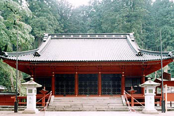 左右に石灯籠が建っている奥に見える、入母屋造で全体が朱色の二荒山神社拝殿の写真
