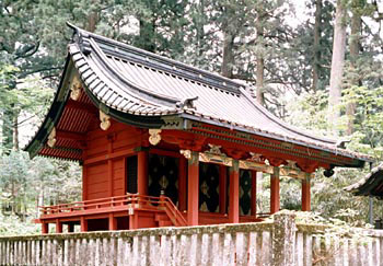屋根が少しカーブを描いた切妻屋根で本殿全体が朱色、周りを石の柵で囲まれている二荒山神社別宮滝尾神社本殿の写真