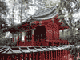 朱色の柵で囲まれた奥に建っている、全体が朱色で切妻屋根の二荒山神社別宮本宮神社本殿の写真