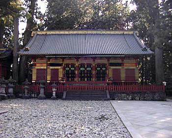 建物へと上がる石階段が中央にあり、切妻造で朱色の低い柵が建物周を囲っている下神庫（しもじんこ）を正面から写した写真