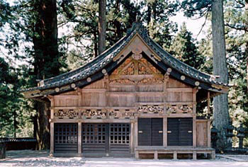 切妻造、シンプルな木造りで壁に彫刻が施されている神厩を正面から写した写真