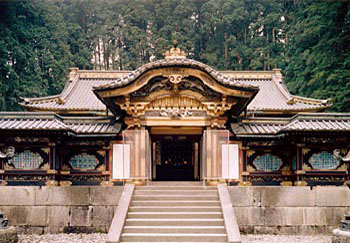 石で出来た階段の上に入口があり、入口の左右に瑞垣が延びており、門の上部には金色で装飾がされている大猷院霊廟唐門を正面から写した写真