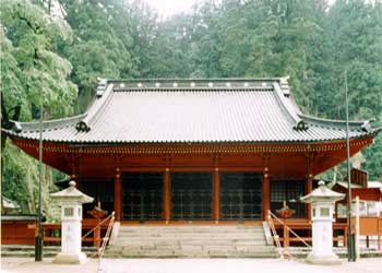 左右に石灯籠が建っている奥に見える、入母屋造で全体が朱色の二荒山神社拝殿の写真
