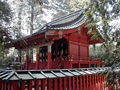 朱色の柵で囲まれた奥に建っている、全体が朱色で切妻屋根の二荒山神社別宮本宮神社本殿の写真