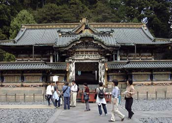 砂利が敷かれた敷地の中央に石畳の参道があり、参道の奥に門が開いた東照宮正面唐門が建っている写真