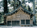 切妻造、シンプルな木造りで壁に彫刻が施されている神厩を正面から写した写真