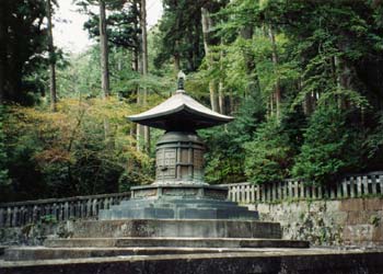 石の土台の上に建っている青銅色をした奥社宝塔の写真