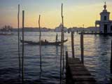 湾に桟橋が伸び、海に一艘の船が浮いているベネチアとその湾（イタリア）の写真