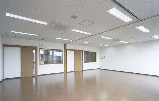壁全体が白く入り口が2ケ所あり、中央で仕切れる学習室の写真