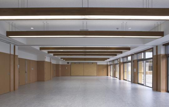 床全体がグレーで右側には大きな入り口が等間隔に設置された会議室の室内全体を映した写真